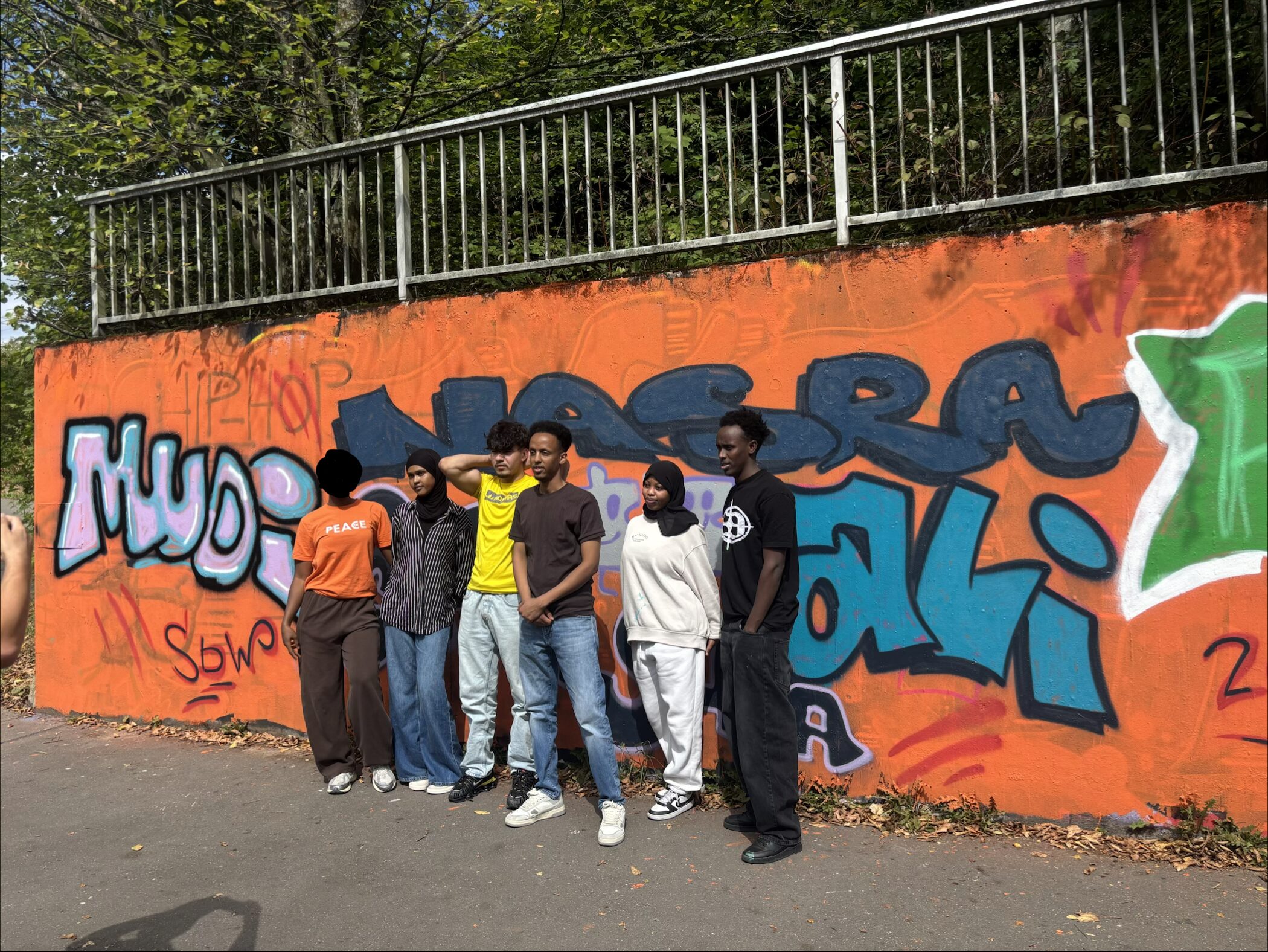 Jugendliche vor ihrem fertigen Graffiti an der legalen Graffitiwand in Lennestadt – Graffiti-Workshop mit Kompass GFO im Kreis Olpe